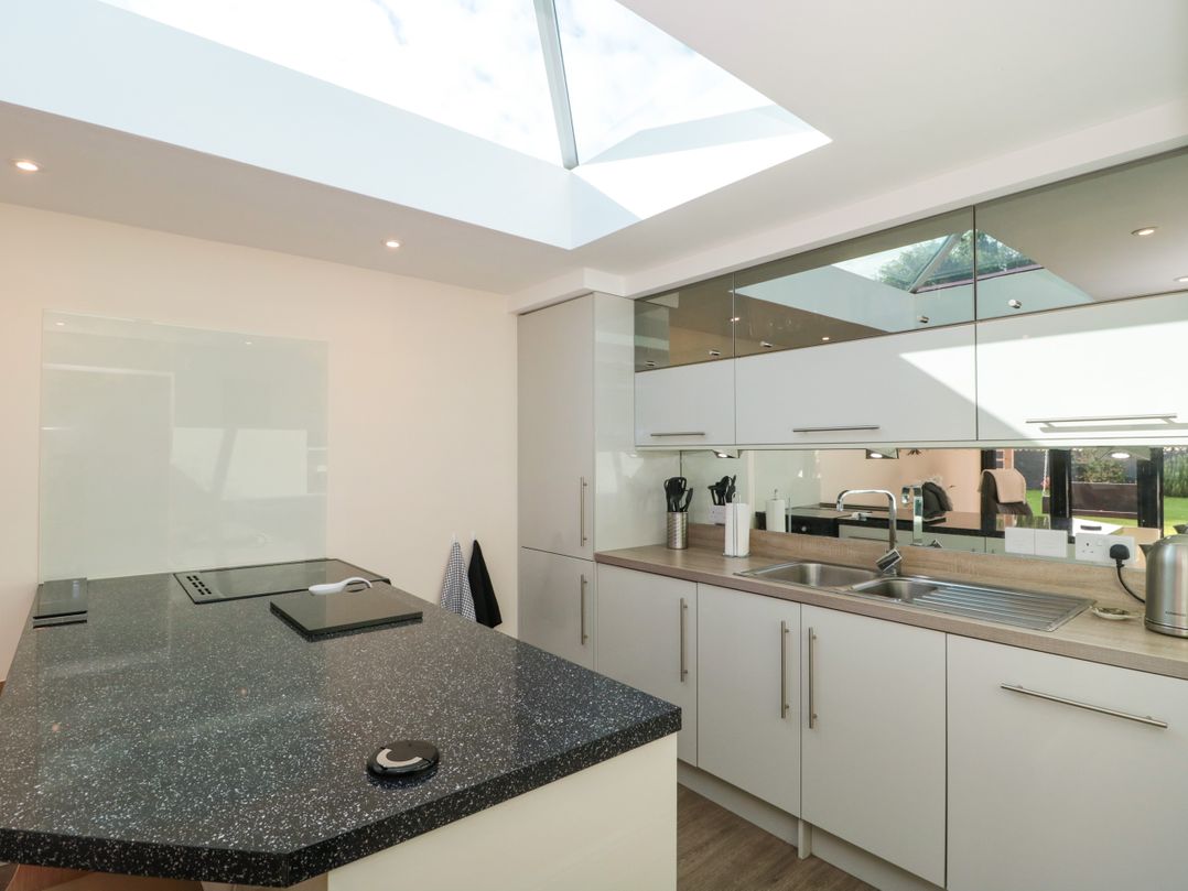 A kitchen with white cabinets a black countertop and a skylight at Minime in Weston-Super-Mare