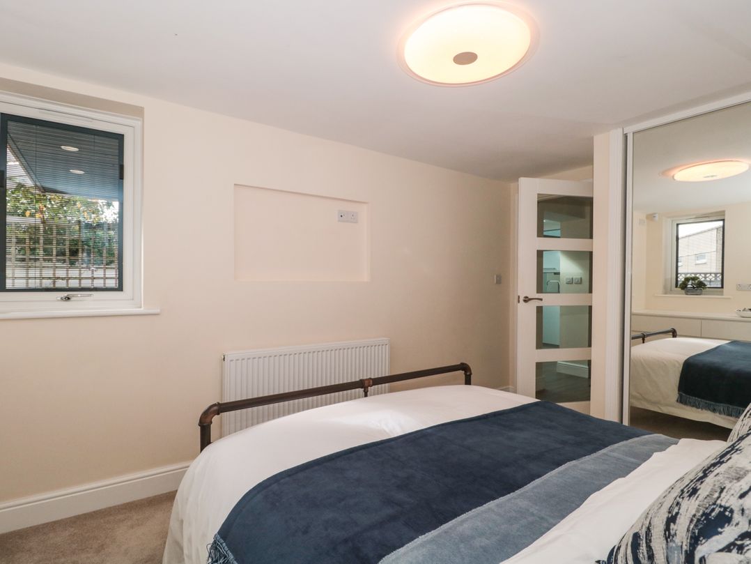 A bedroom with a bed a window a radiator and a mirrored wardrobe at Minime in Weston-Super-Mare