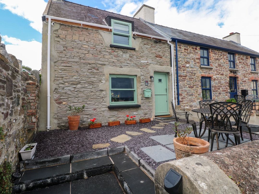 An outdoor view of the exterior of a house with seating at 2 Strand Cottages in Laugharne