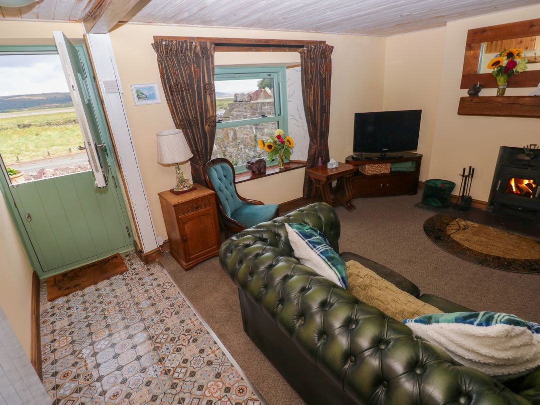 A living room with a sofa and television at 2 Strand Cottages in Laugharne