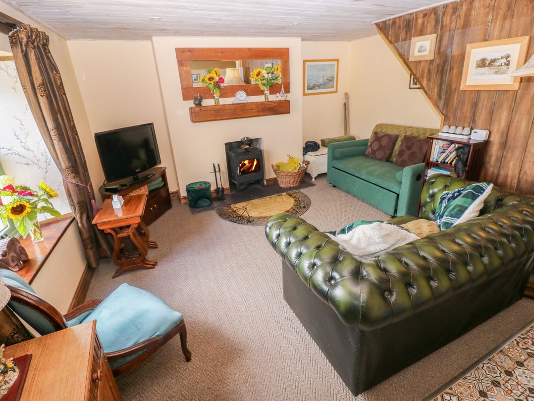 A living room with furniture and a fireplace at 2 Strand Cottages in Laugharne