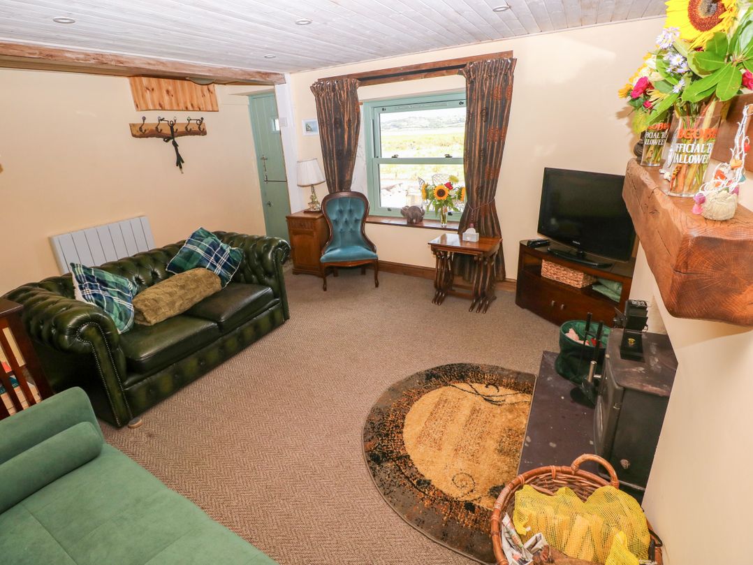 A living room with a sofa, chair, and television at 2 Strand Cottages, Laugharne