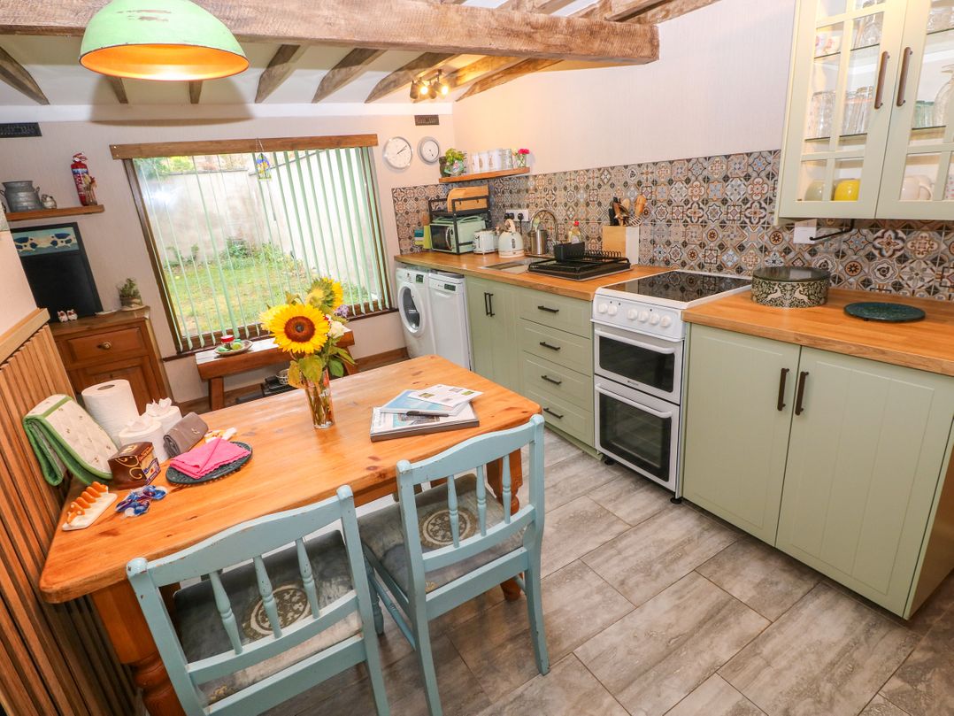 A kitchen with a table and chairs at 2 Strand Cottages in Laugharne