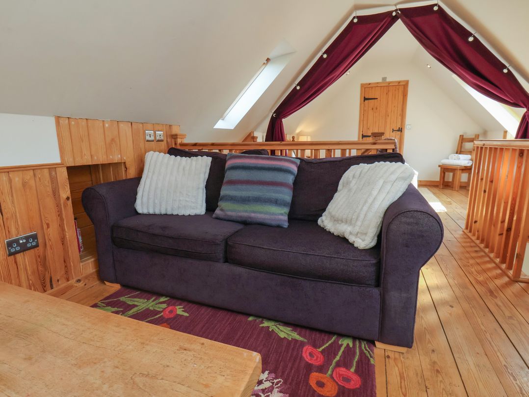 A loft space with a sofa and wooden table at Horseshoe Cottage Ingleby Greenhow near Great Ayton