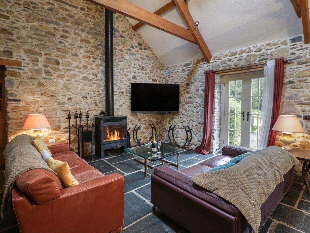 A living room with a sofa, coffee table, and fireplace at St Dogwells Barn near Wolfscastle