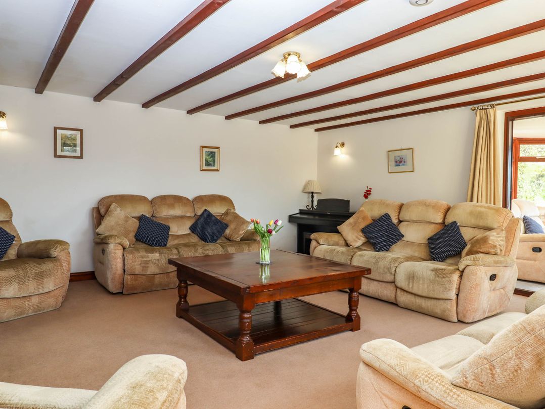 A living room with beige sofas a wooden coffee table and ceiling beams at Valley House Halberton near Tiverton