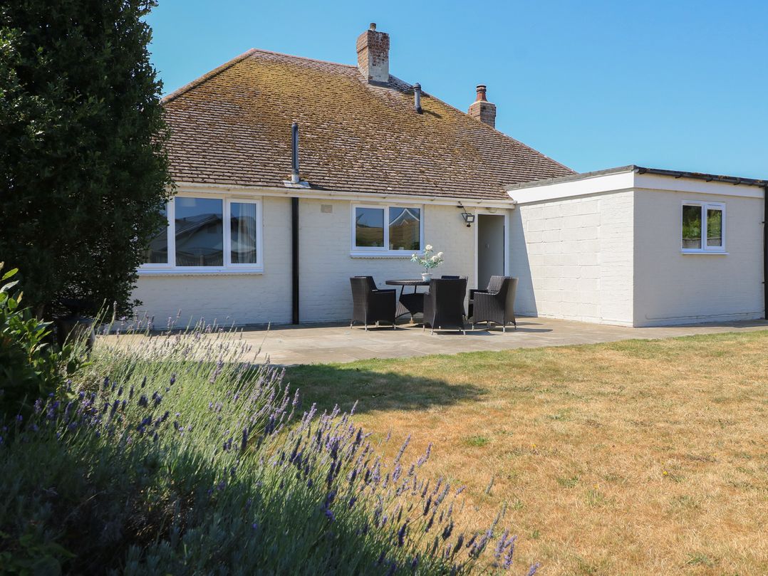 A house with a patio and chairs at Bayview Cottage in Southbourne