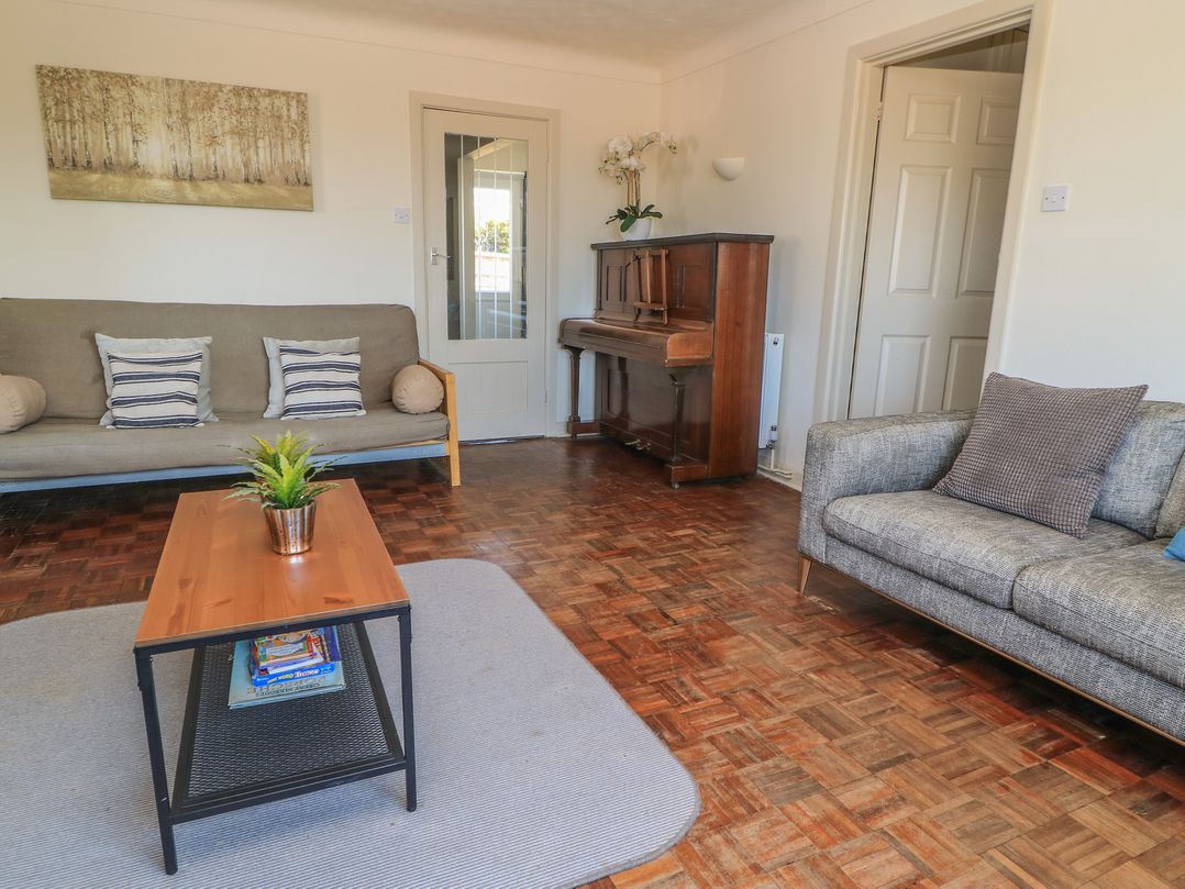 A living room with a piano and sofa at Bayview Cottage in Southbourne