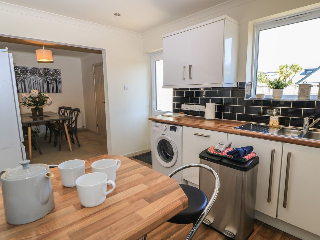 A kitchen with a washing machine and table at Bayview Cottage in Southbourne