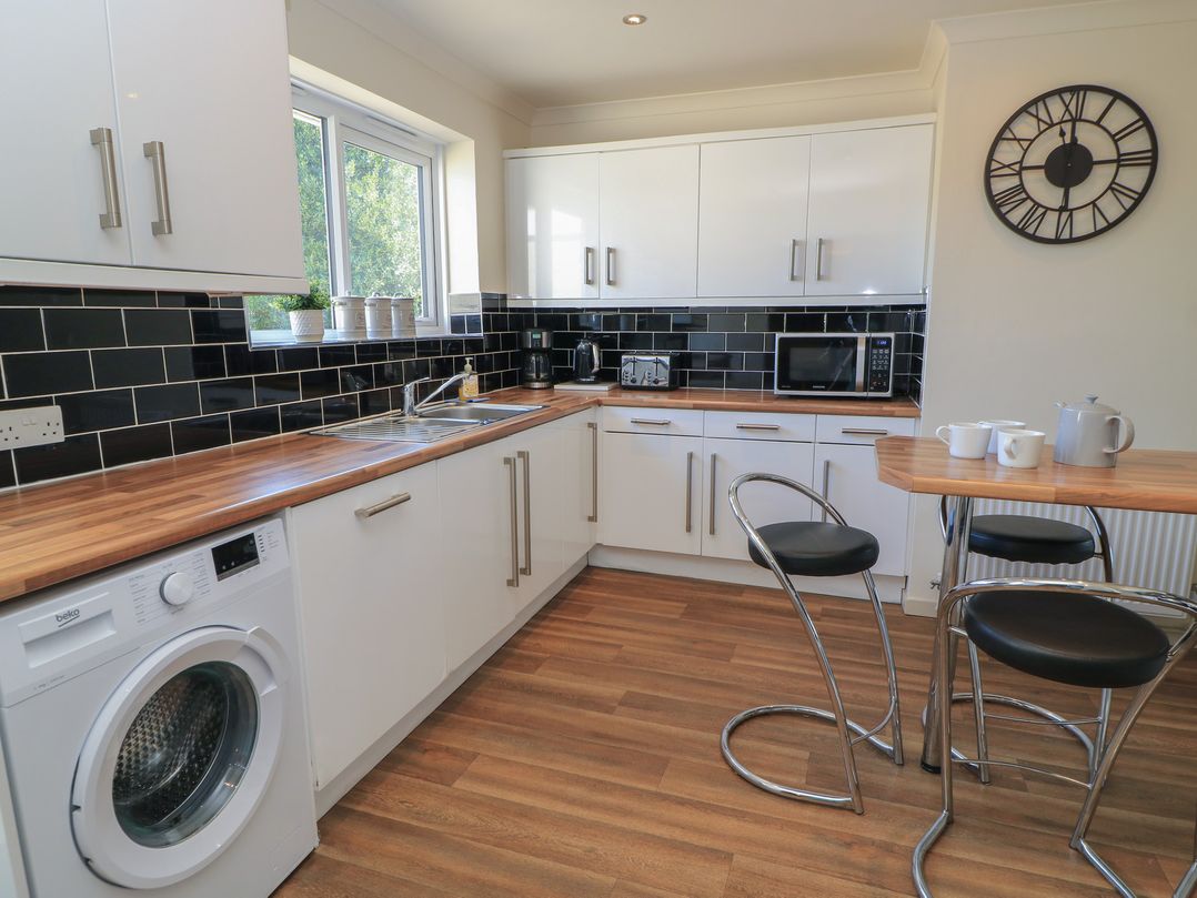A kitchen with appliances and a bar table at Bayview Cottage in Southbourne