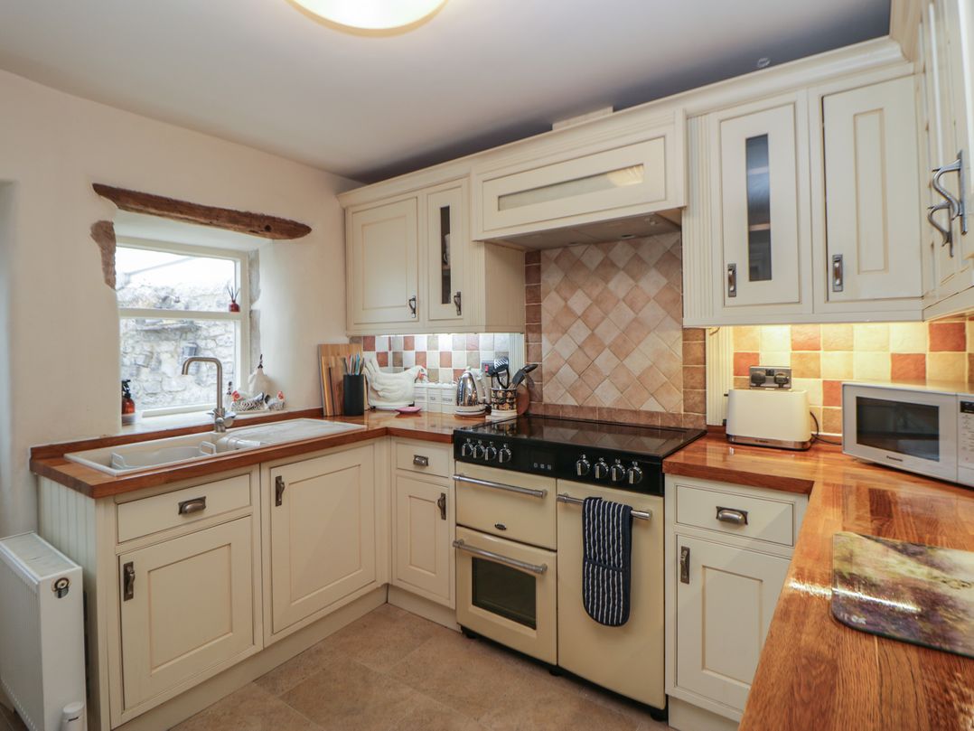 A kitchen with a stove and sink at Rose Cottage in Hartington
