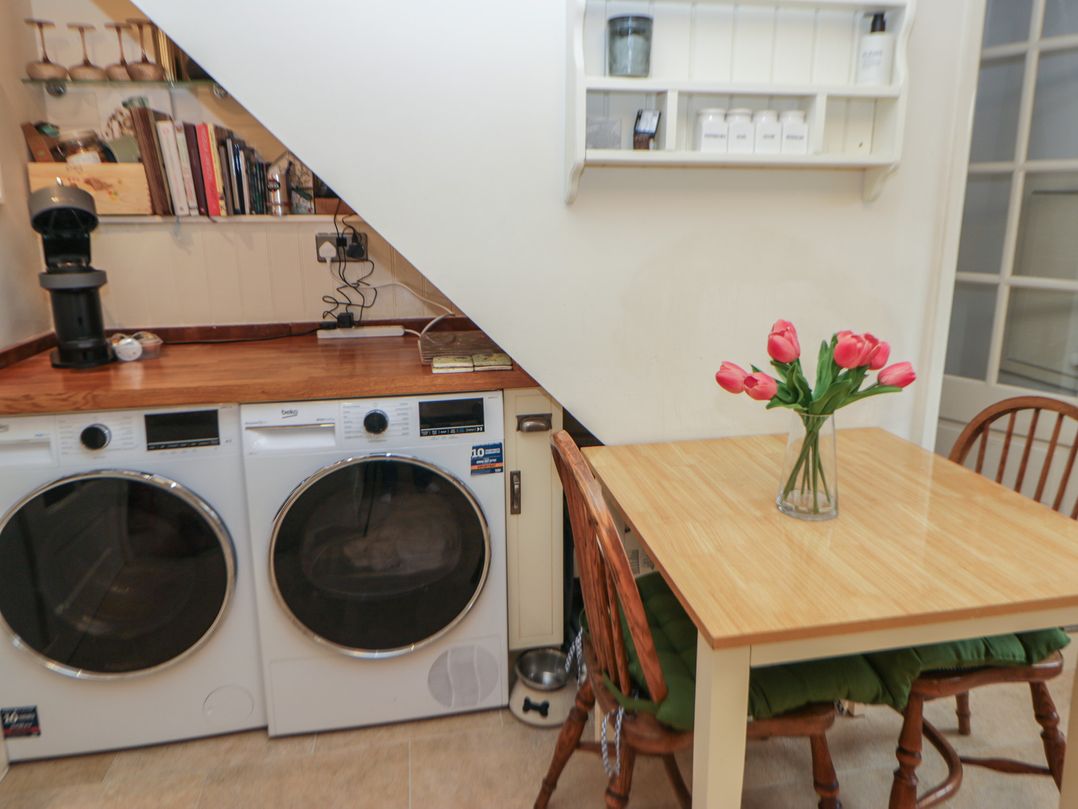A kitchen with washing machine, dryer, and a table at Rose Cottage in Hartington