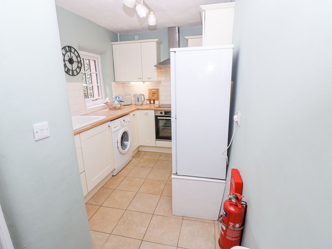 A kitchen with a refrigerator washing machine oven and fire extinguisher at 3 Eden View in Lazonby