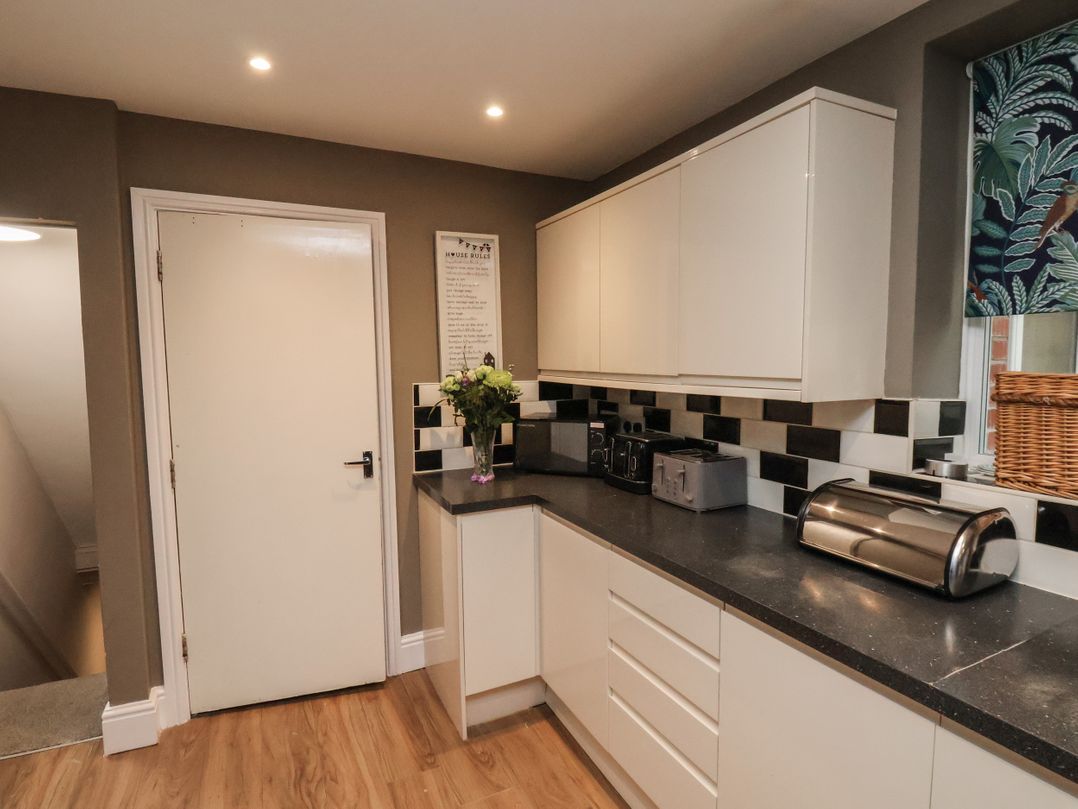 A kitchen corner with white cabinets black countertop a toaster microwave and flower vase at Sail Lodge in Scarborough