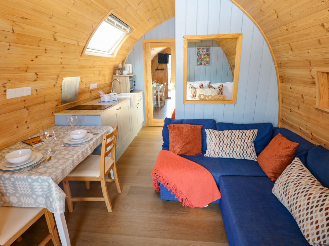 A living room with a sofa and dining area at Ty Twt Teifi in Llanddewi-Brefi