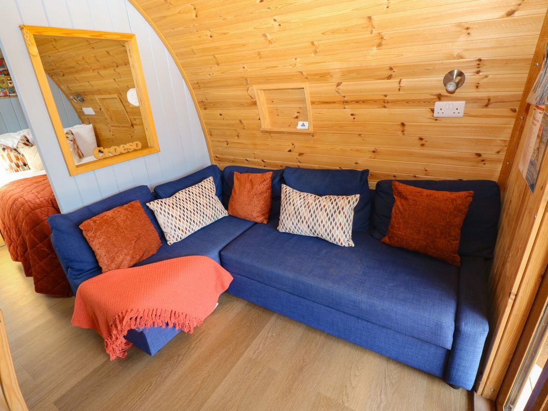 A snug with a blue sofa and throw blanket at Ty Twt Teifi, Llanddewi-Brefi