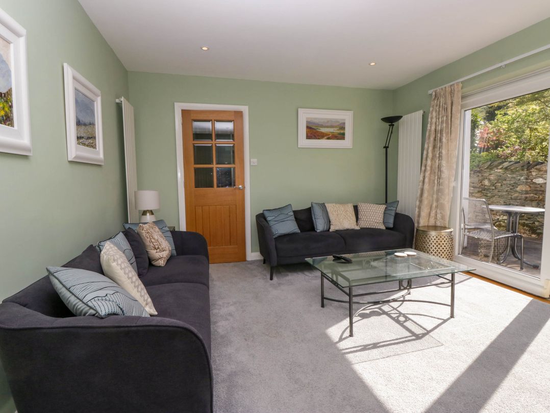 A sitting room with two sofas glass coffee table and a door at Beckside Ambleside