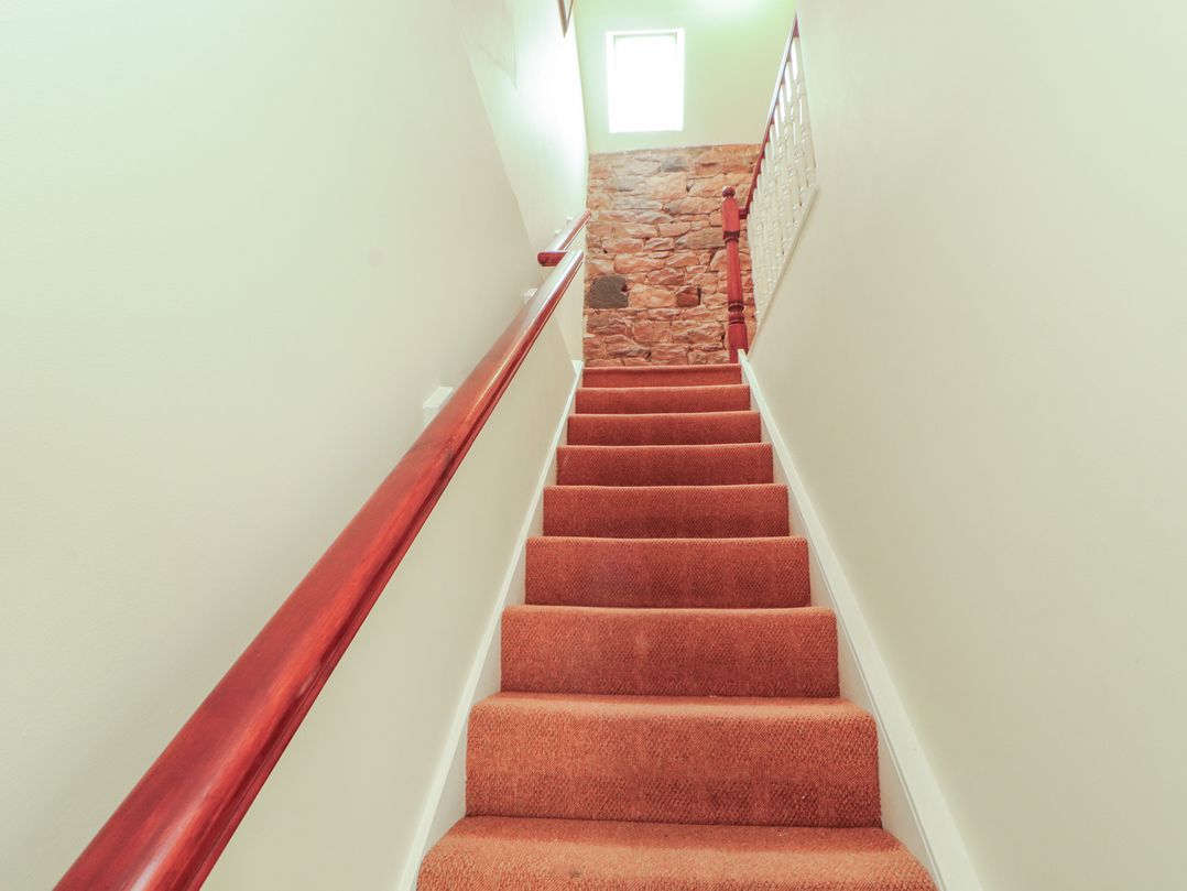 A staircase with carpet and window at Millers Cottage in Seaville near Wigton