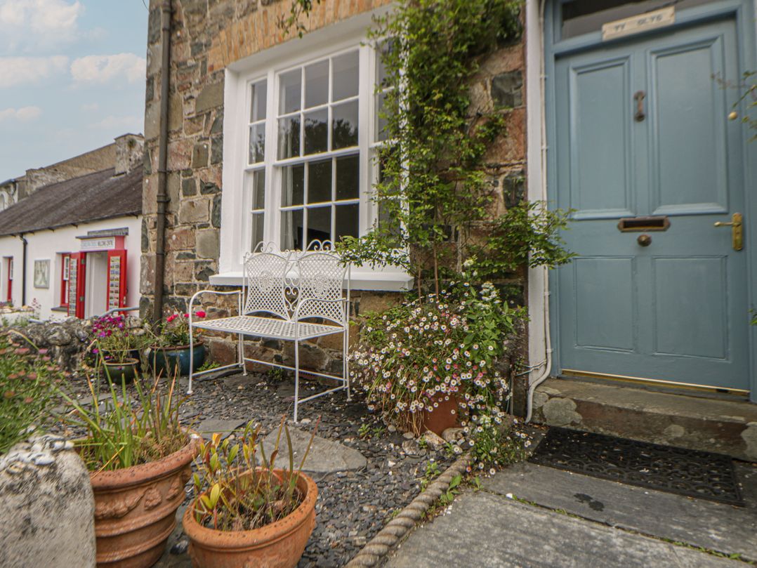 An outdoor space with a bench, flowerpots and plants at Ty Clyd in Newport, Pembrokeshire