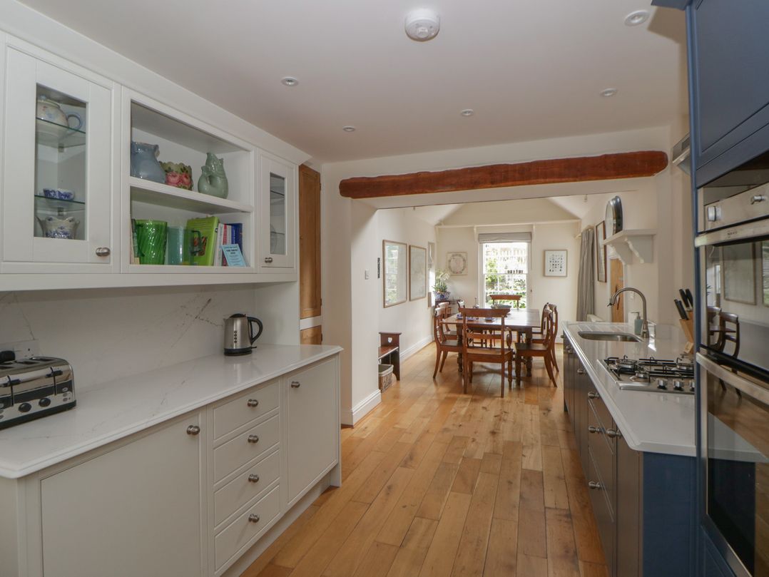 A kitchen with cabinets, a kettle, and a dining area at Ty Clyd in Newport, Pembrokeshire