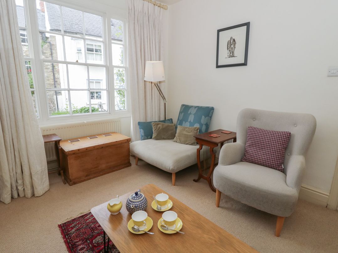 A living room with a sofa, armchair, coffee table, and a window at Ty Clyd in Newport, Pembrokeshire