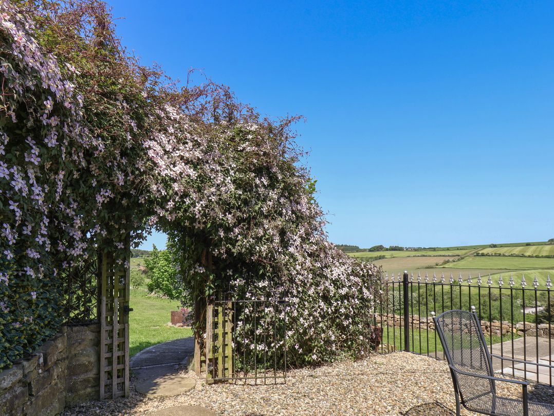 An outdoor area with flowers and a gate at Wayside Farm Cart Cottage in Cloughton near Burniston