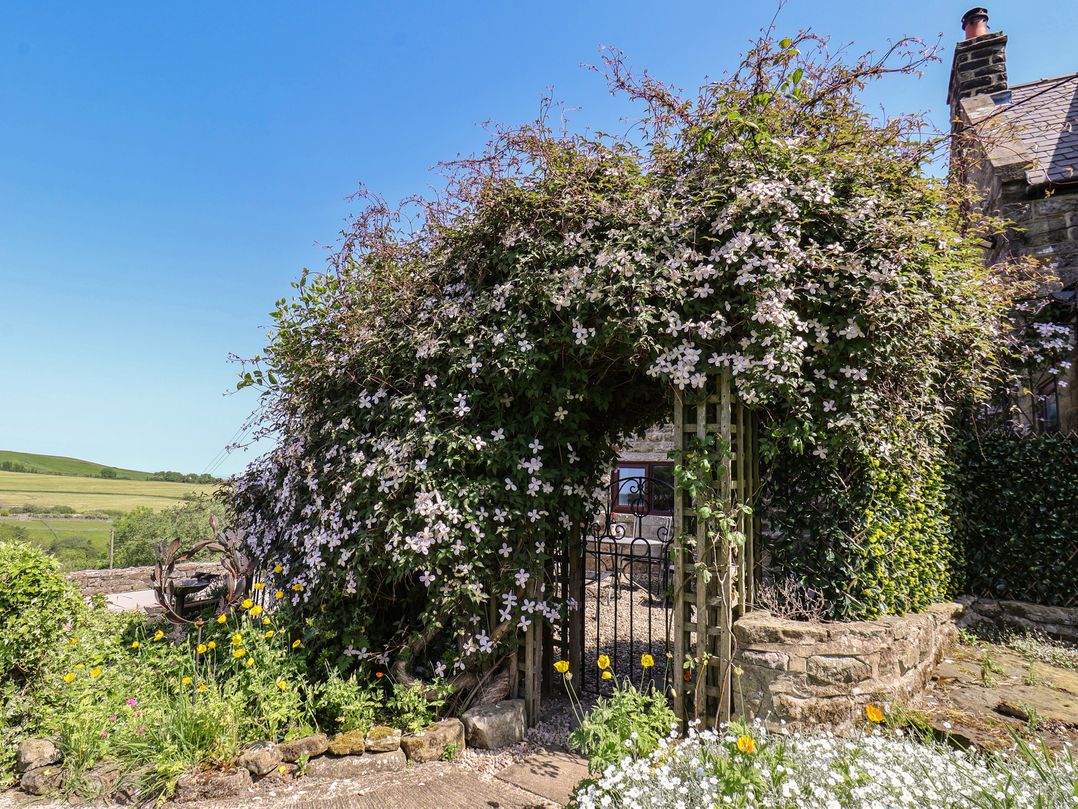A garden with flowers and a gate at Wayside Farm Cart Cottage in Cloughton near Burniston