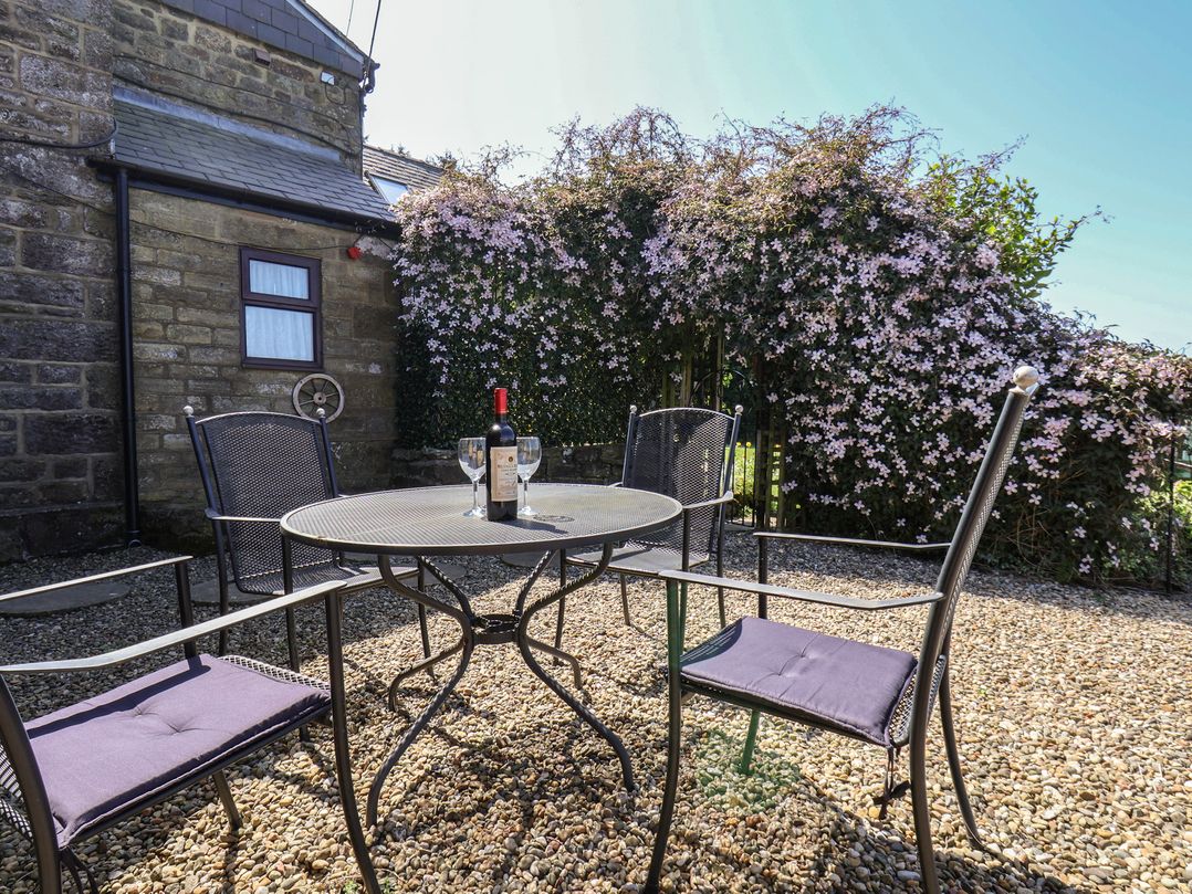 An outdoor seating area with a table and chairs at Wayside Farm Cart Cottage in Cloughton near Burniston