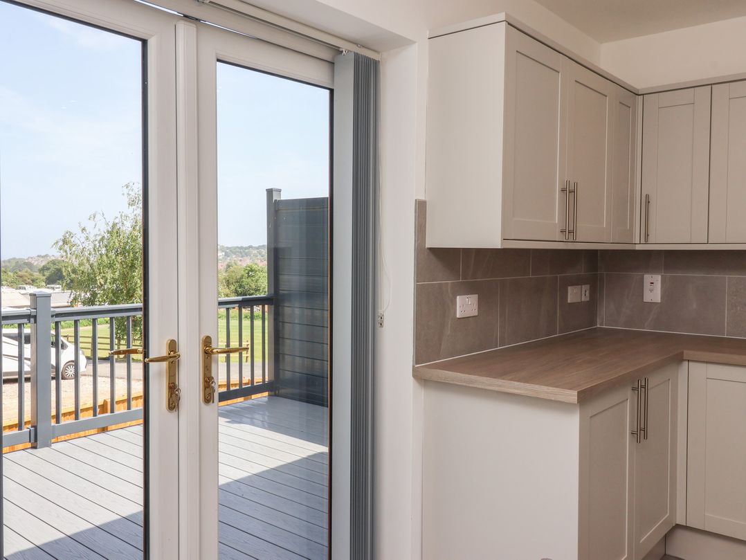 A kitchen with cabinets and double doors leading to a deck at Castle View in Scarborough