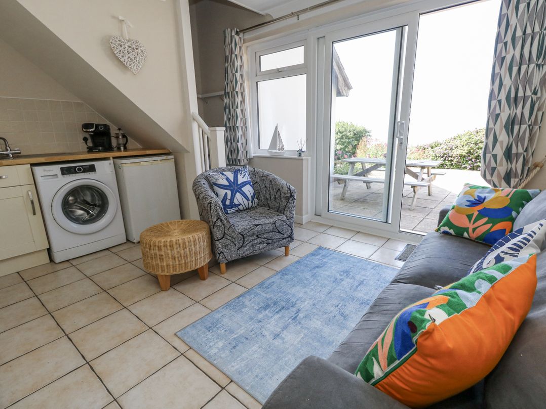 A living room with a washing machine and sofa at Sea Spray in Bowleaze