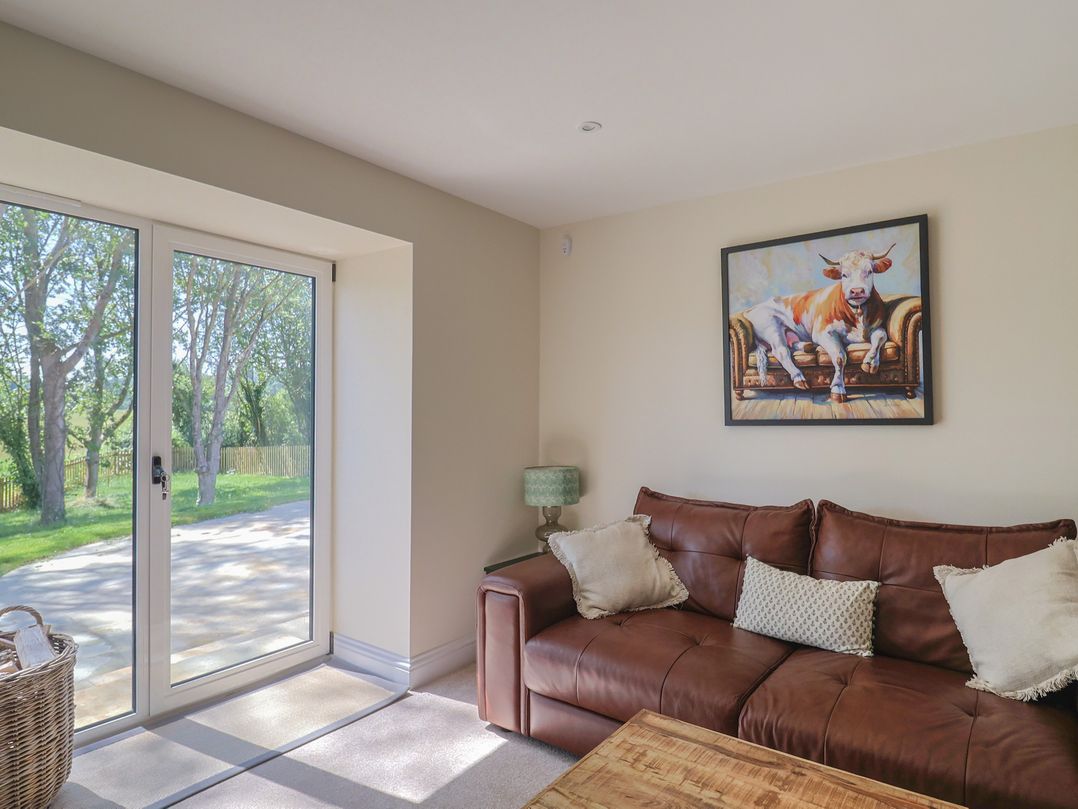 A living room with a sofa and sliding doors at The Fox Den in East Coker