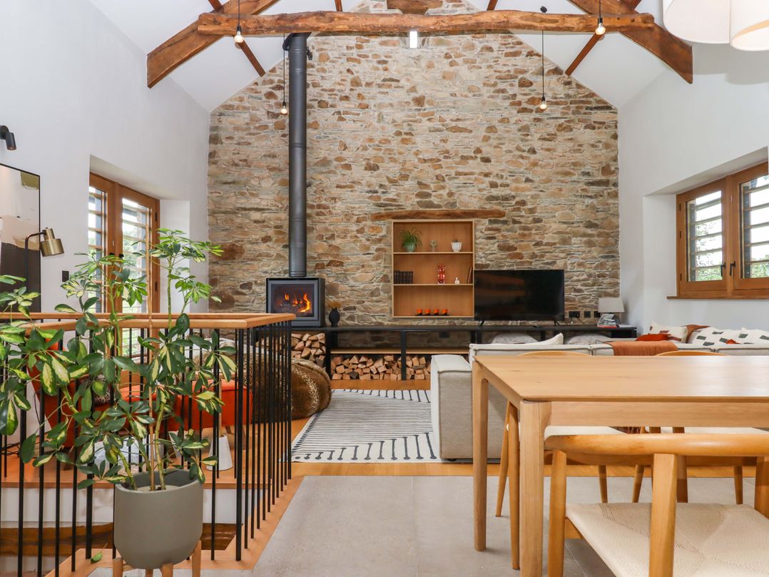 A living room with a fireplace and seating area at Lower Walreddon Barn Tavistock
