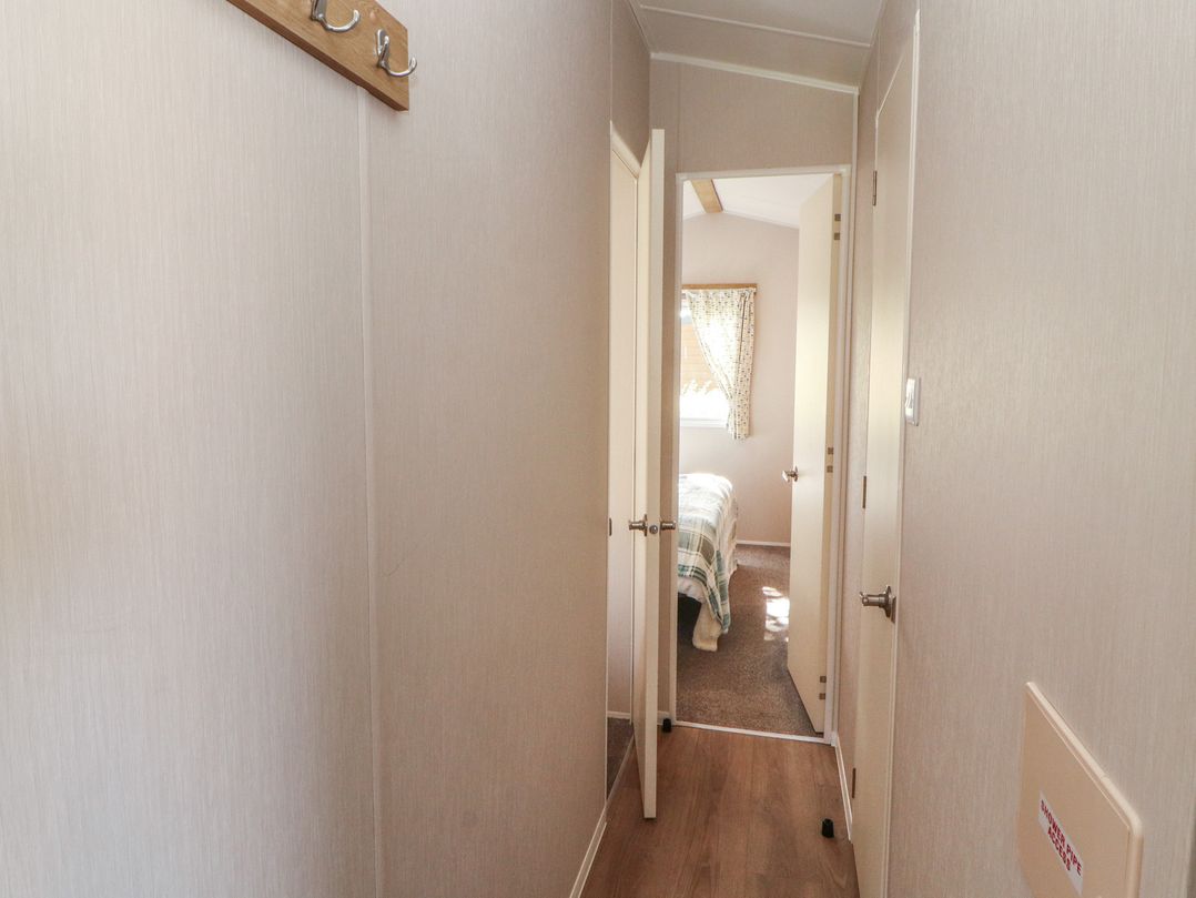 A hallway with doors to rooms and a window at Barnes Retreat in Carnforth