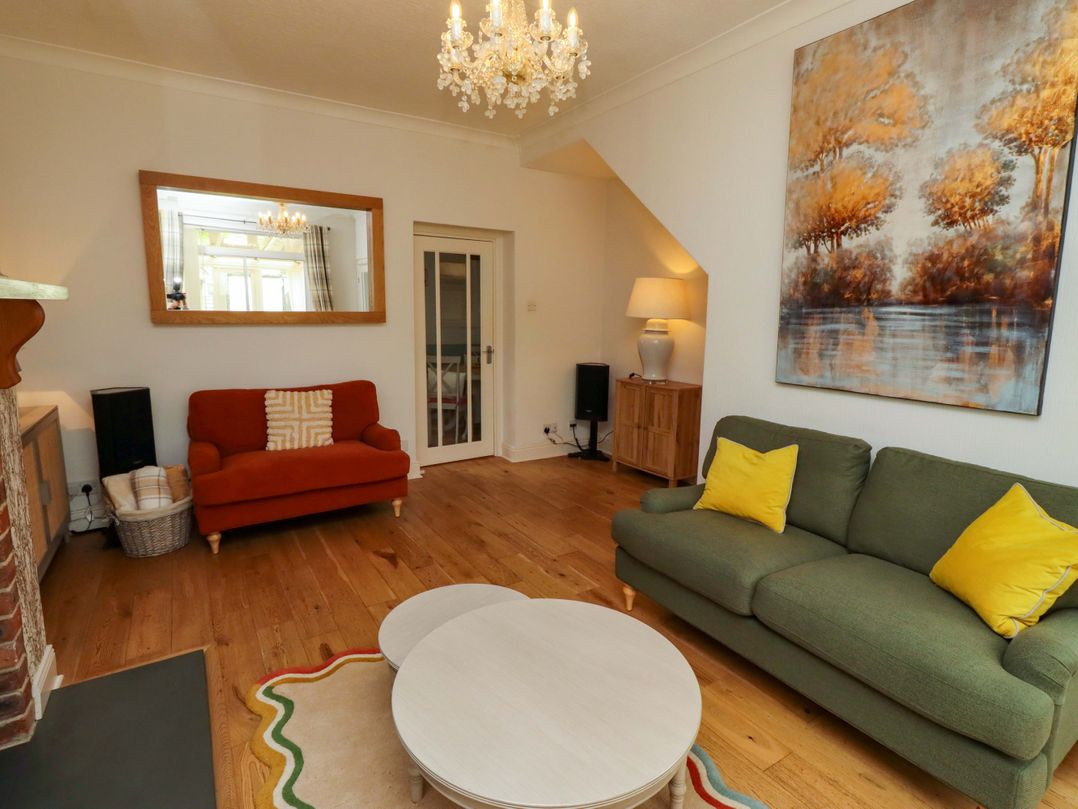 A living room with orange and green sofas and a coffee table at Rose Briar Cottage in Morpeth