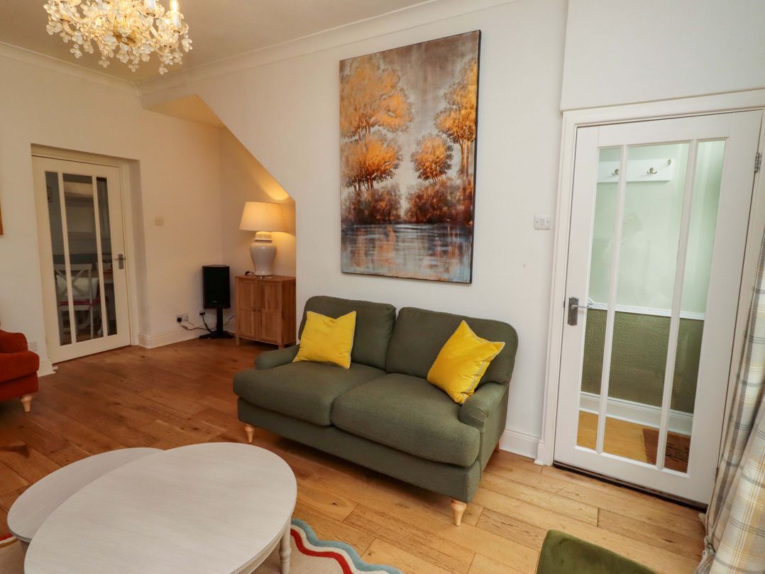 A living room with a green sofa and a coffee table at Rose Briar Cottage in Morpeth