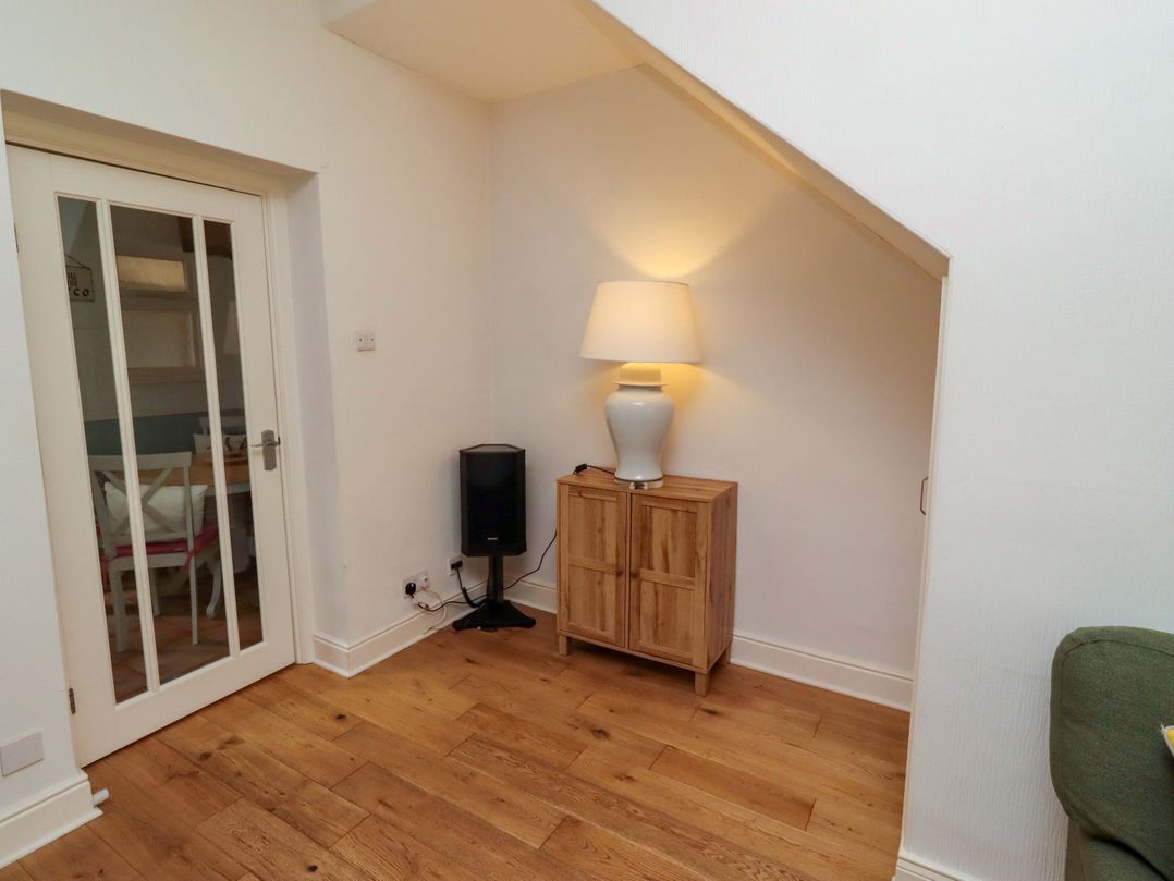A snug with a cabinet and lamp at Rose Briar Cottage in Morpeth