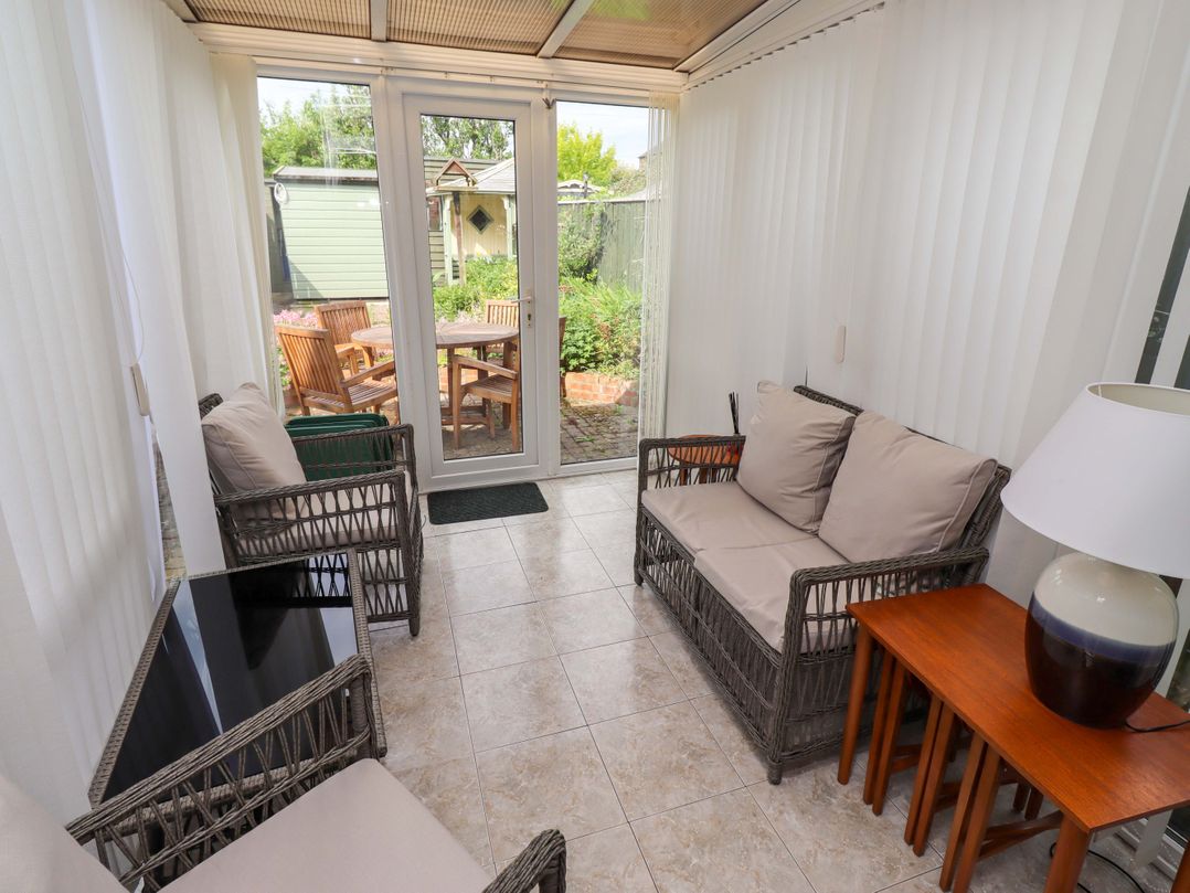 A conservatory with seating and a door leading to the garden at Rose Briar Cottage in Morpeth