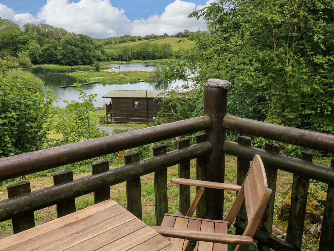 A view from a wooden balcony overlooking a lake at Ash Lodge in Mynydd Cerrig near Porthyrhyd