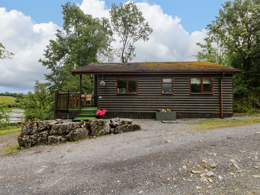 A log cabin with trees and a planter at Ash Lodge in Mynydd Cerrig near Porthyrhyd