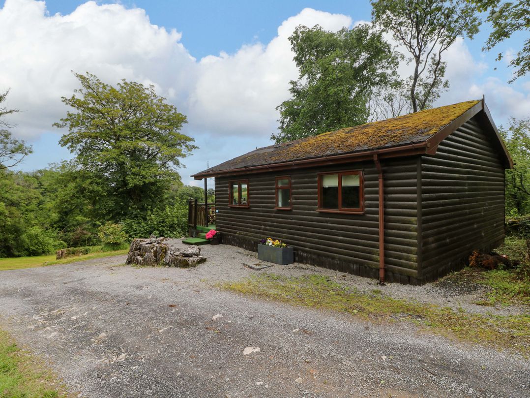 A log cabin with a gravel path and planter at Ash Lodge Mynydd Cerrig near Porthyrhyd