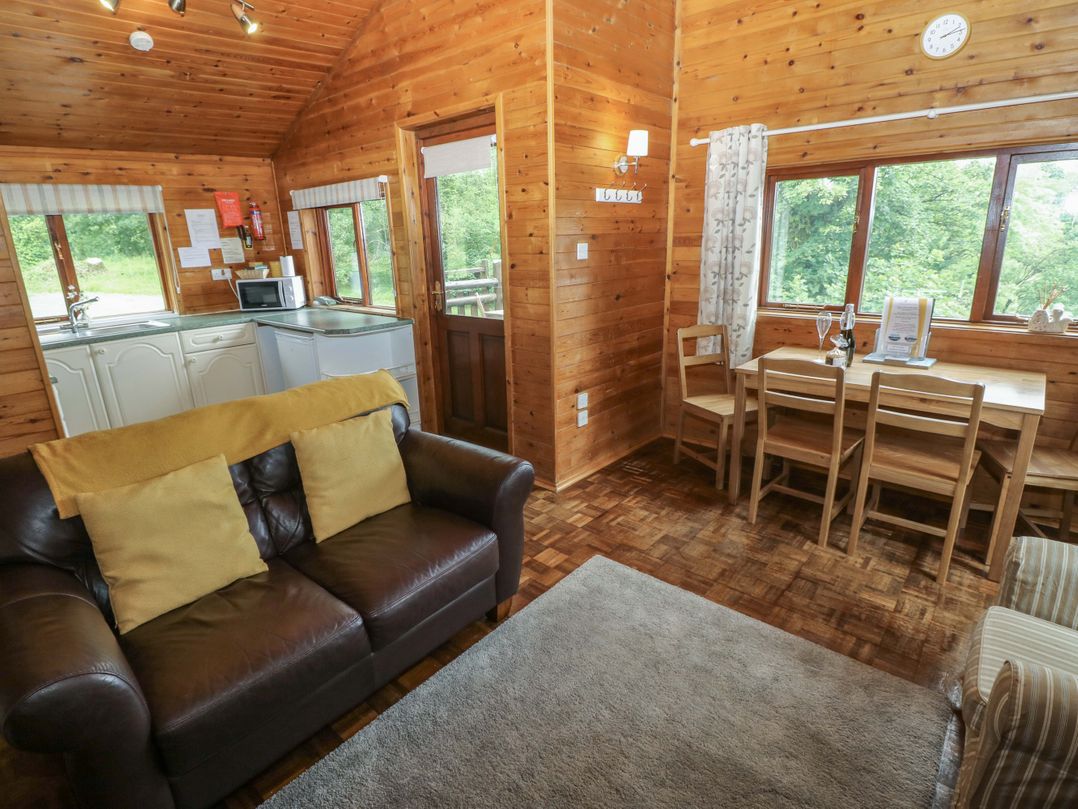 A living room with a sofa and dining area at Ash Lodge Mynydd Cerrig near Porthyrhyd