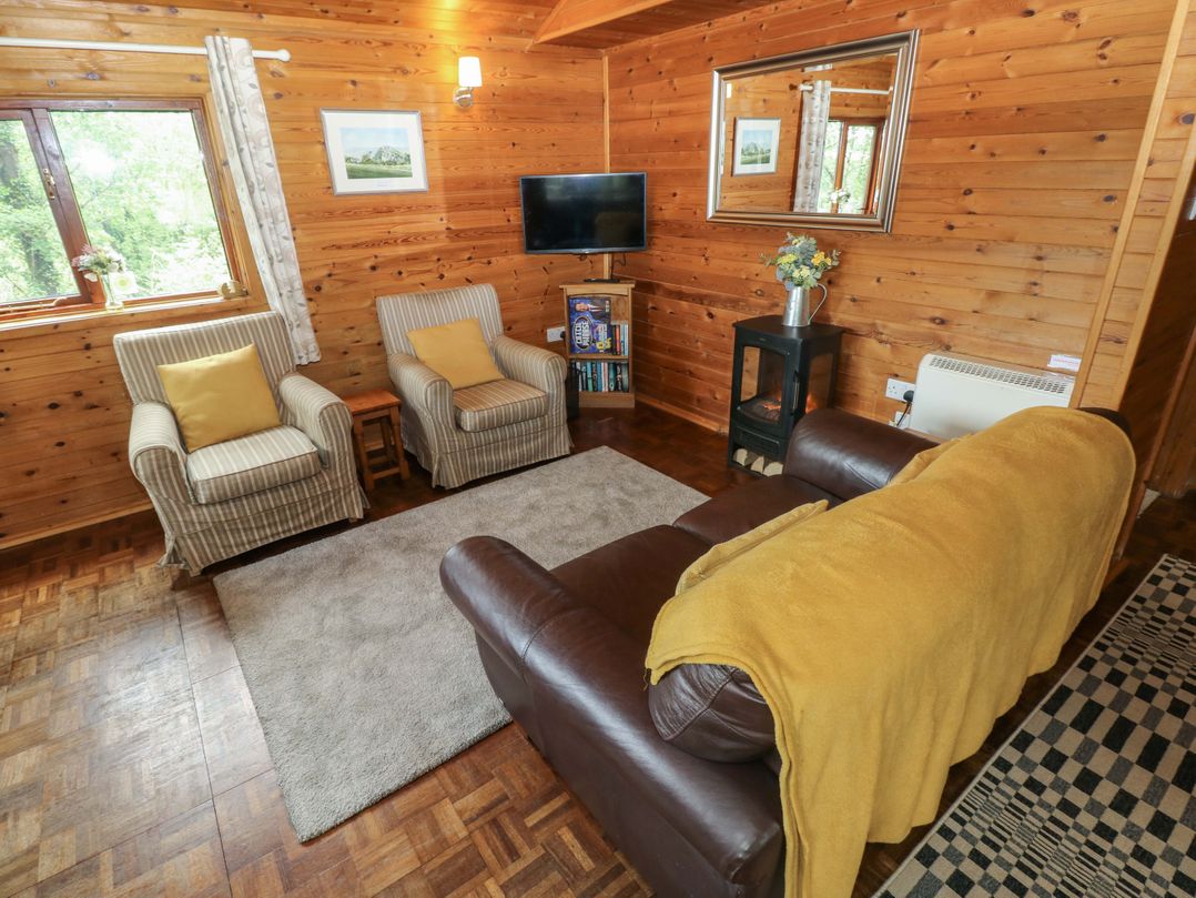 A living room with a sofa and armchair at Ash Lodge near Mynydd Cerrig