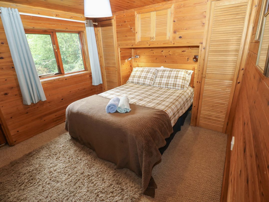 A bedroom with a bed and window at Ash Lodge in Mynydd Cerrig near Porthyrhyd