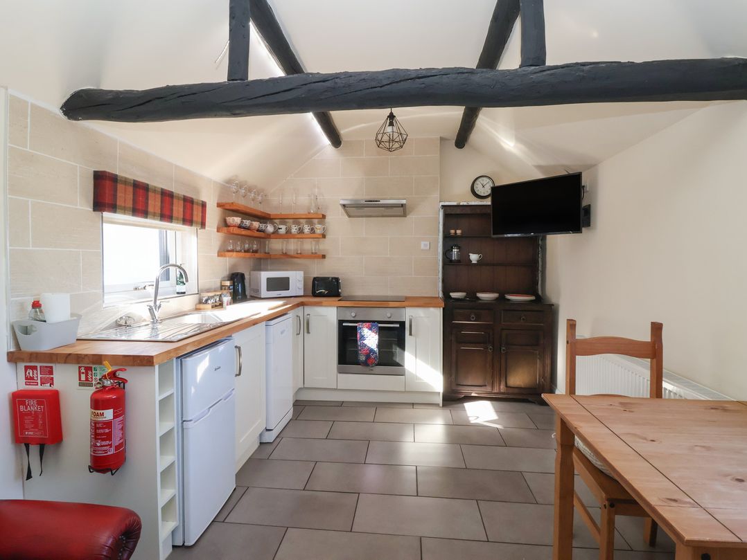 A kitchen with appliances and dining table at Cowshed Cottage East Knapton near Rillington