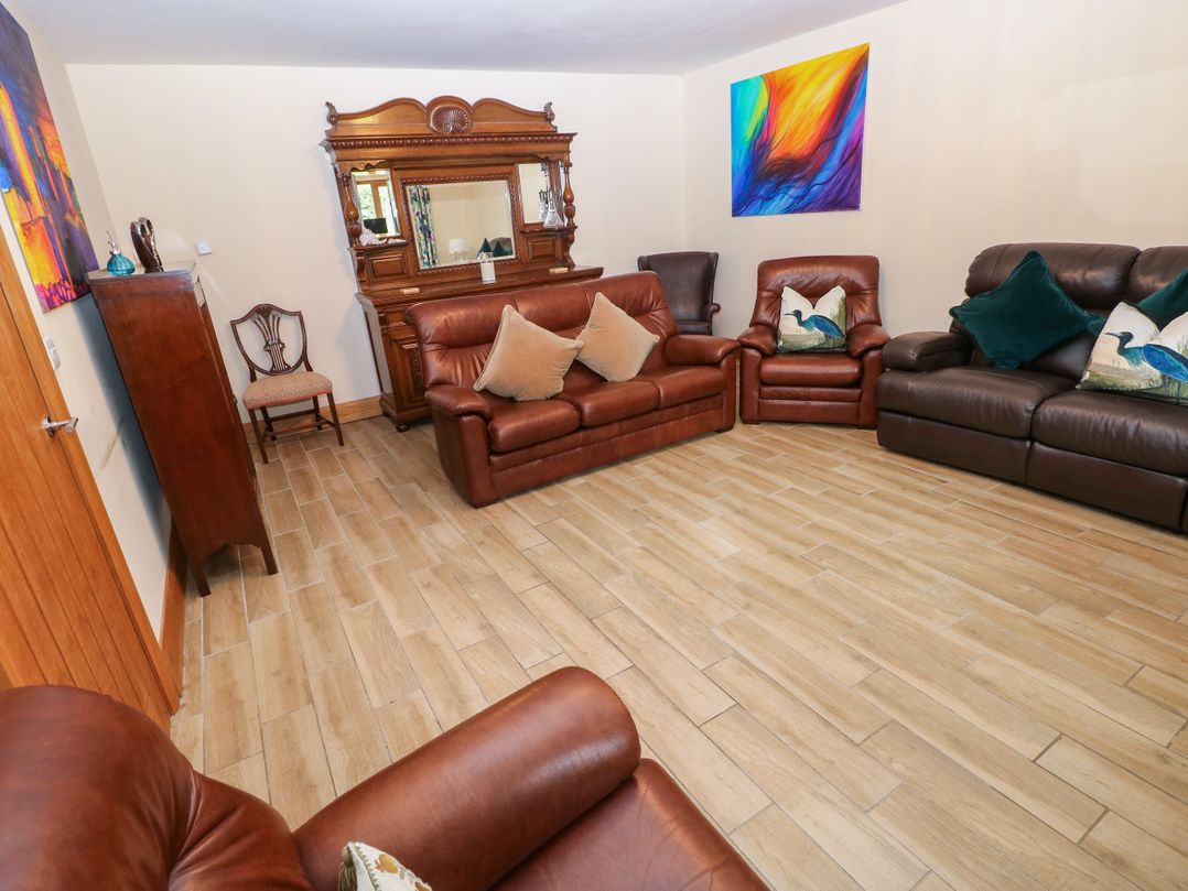 A living room with brown sofas and an ornate mirror at Ty-Gan Dderwen in Llangennech, Llanelli