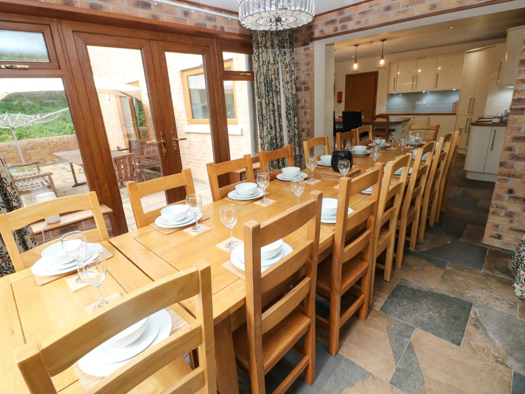 A dining room with a long table set for a meal at Ty-Gan Dderwen, Llangennech, Llanelli