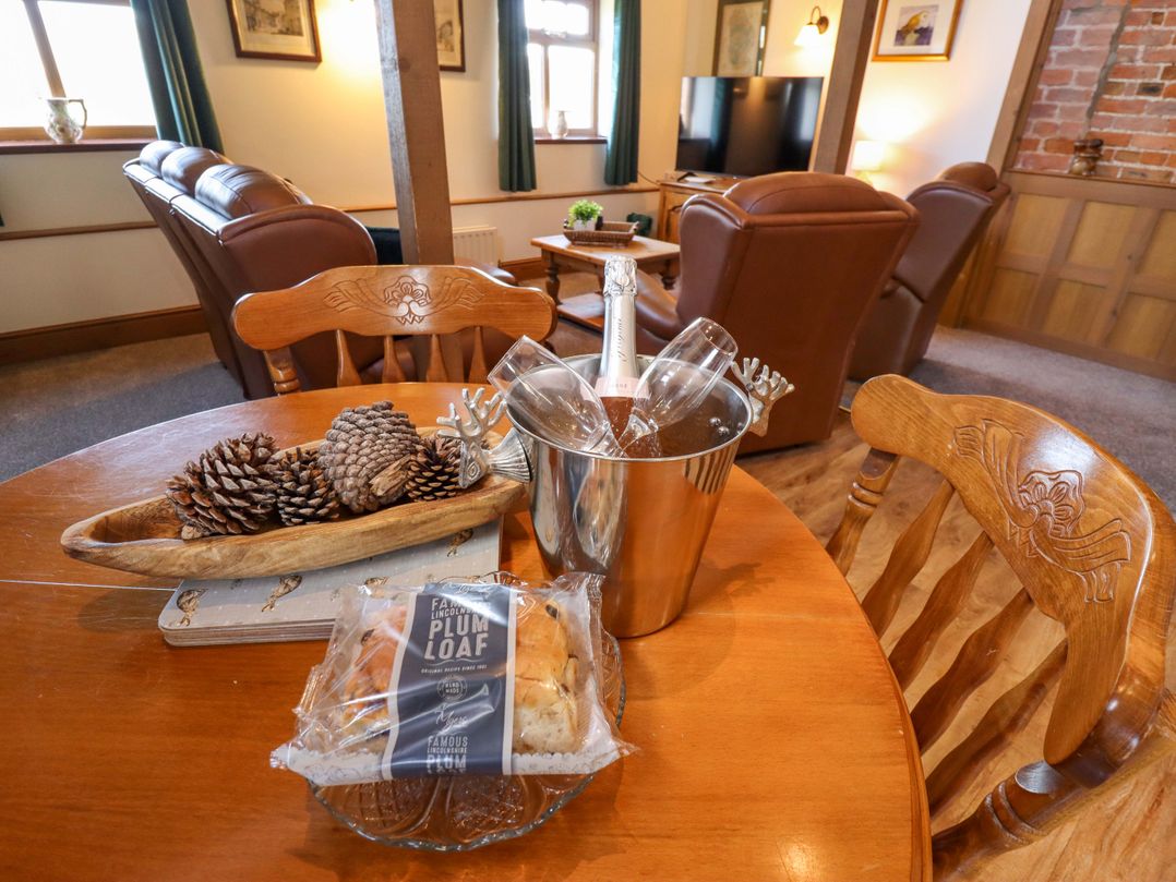 A living room with a table set with champagne and a plum loaf at Barn Owl near Louth