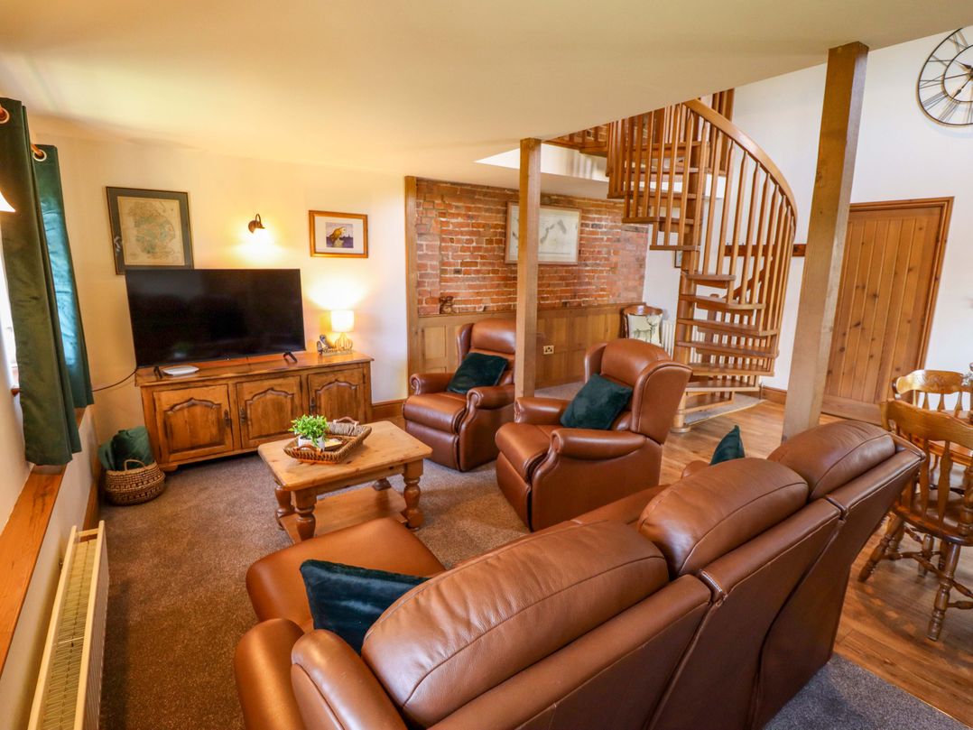 A living room featuring a television and brown leather furniture at Barn Owl near Louth