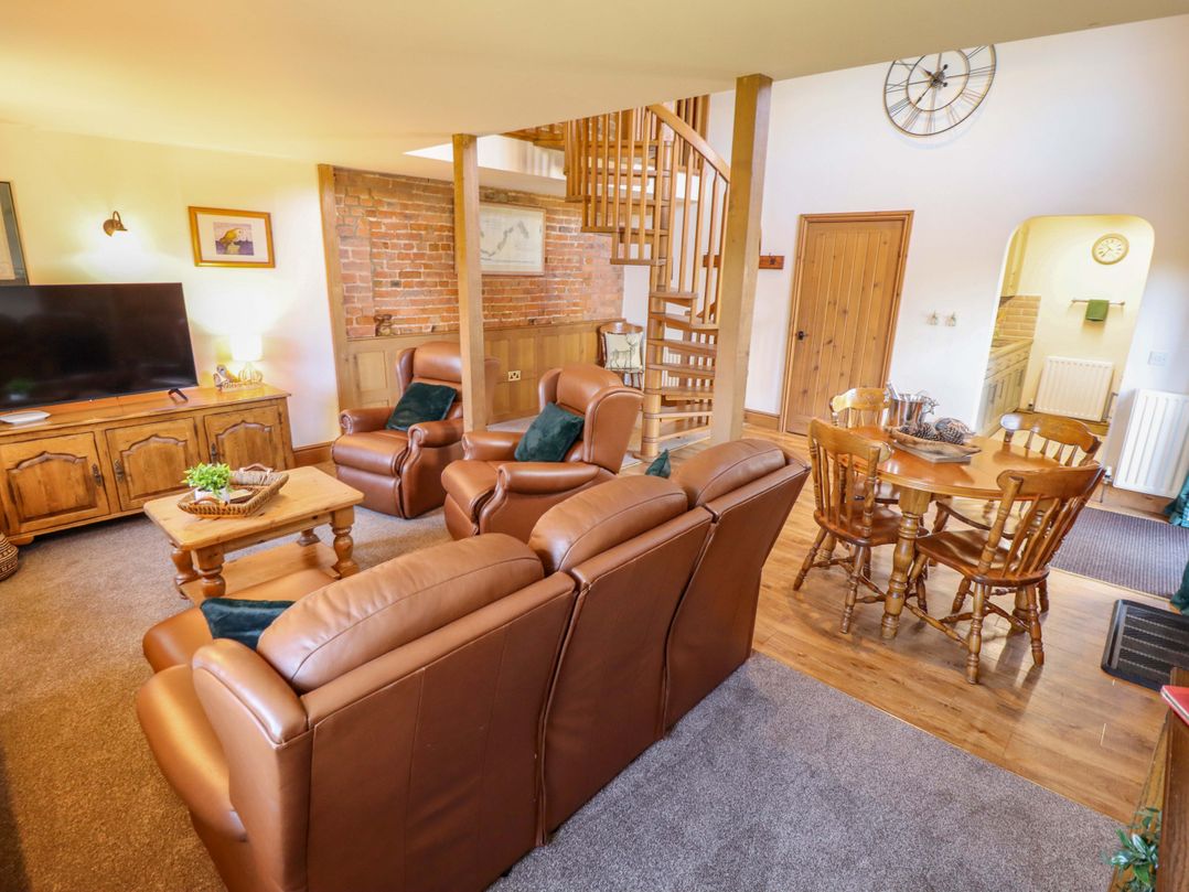 A living room with a sofa and dining area at Barn Owl near Louth