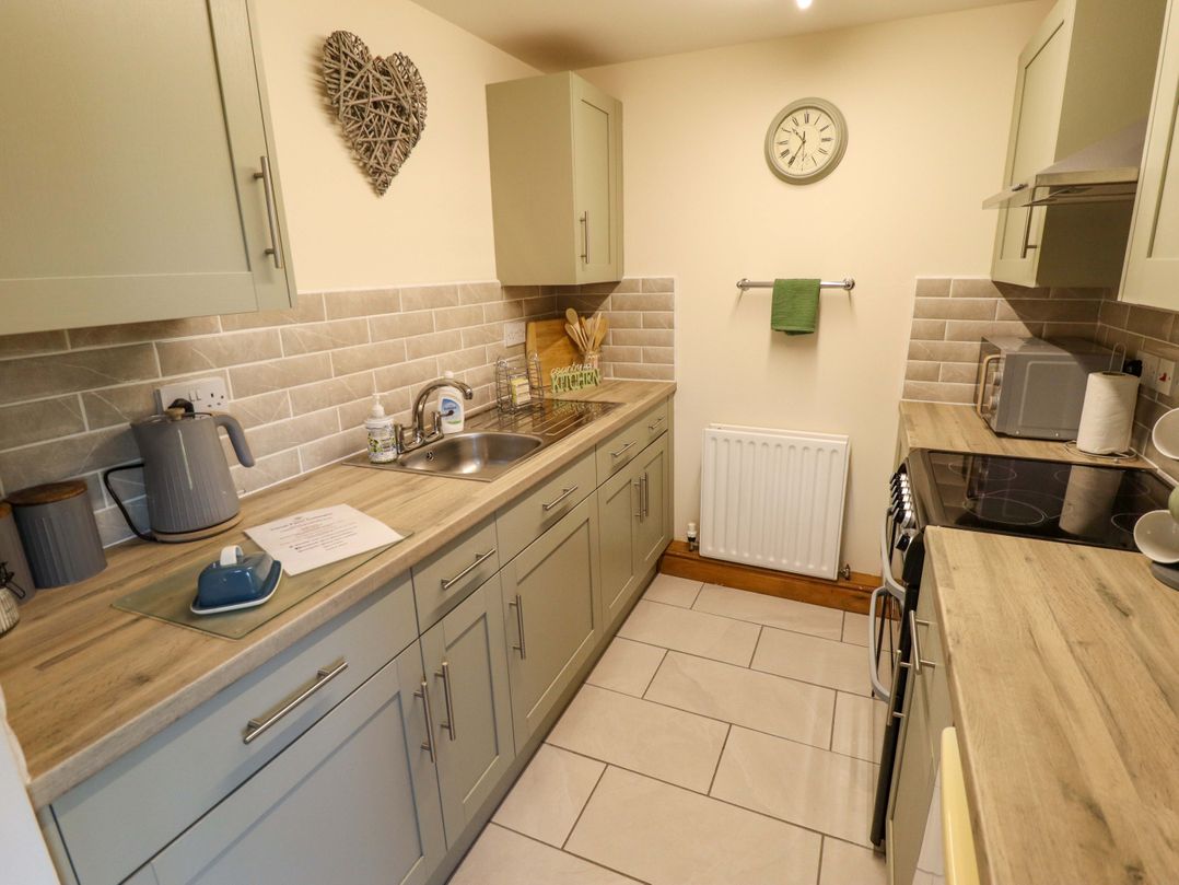 A kitchen with cabinets, kettle, microwave, and sink at Barn Owl near Louth